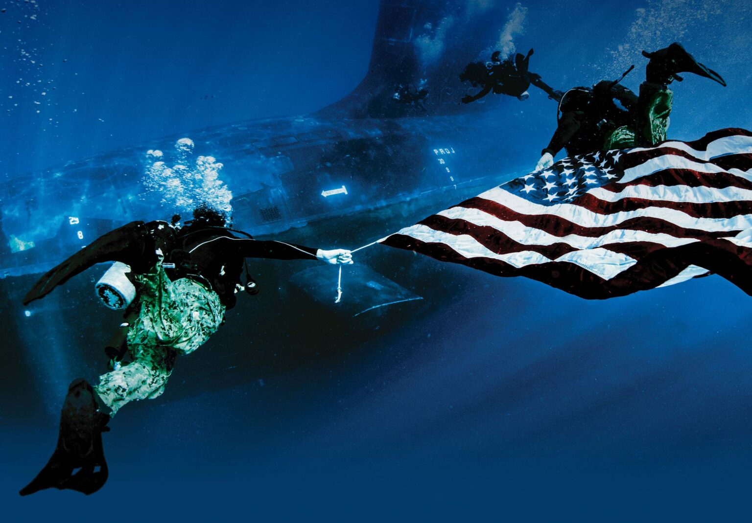 Navy SEAL divers underwater, carrying an American flag, symbolizing strength and dedication.